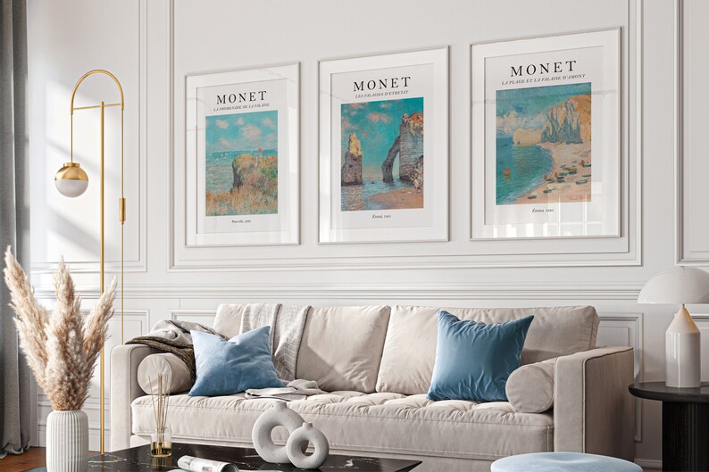 Puede incluir: Tres impresiones de arte enmarcadas de paisajes marinos de Claude Monet. Las impresiones est&aacute;n en marcos blancos y presentan el texto "MONET" y el t&iacute;tulo de cada pintura. Las pinturas son "La Corniche de la Plage", "Les falaises d'Etretat" y "La Plage et la falaise d'Etretat".