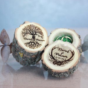 Op de afbeelding: Twee houten ringendozen met gegraveerde ontwerpen. Een doos heeft een boom met wortels en de tekst "Daniel & Parisian 11/30/21". De andere doos heeft geweien en de tekst "Daniel & Parisian 11/30/21".
