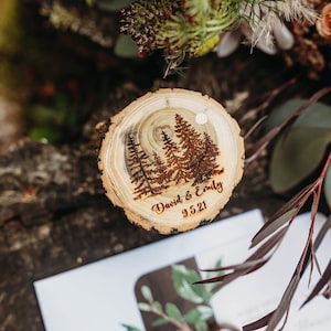 以下が含まれることがあります： 森のシーンが焼かれたデザインと「David & Emily 9.5.21」というテキストが書かれた木の切り株。