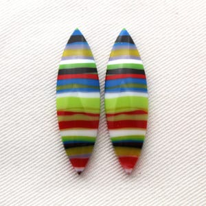 Op de afbeelding: Twee bladvormige oorbellen met horizontale strepen in rood, groen, blauw, zwart, geel en wit. De oorbellen zijn geplaatst tegen een witte achtergrond.