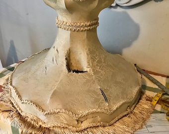 May include: A cream-colored lampshade with a scalloped edge and a fringe trim. The lampshade has a floral pattern and is slightly damaged.