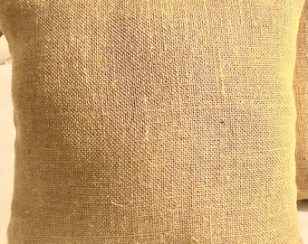 May include: Two brown burlap throw pillows with a woven texture.