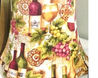 May include: A lampshade with a white background and a colorful design of grapes, wine bottles, and wine glasses. The design includes the words "Merlot Rose" and "Pinot Noir".