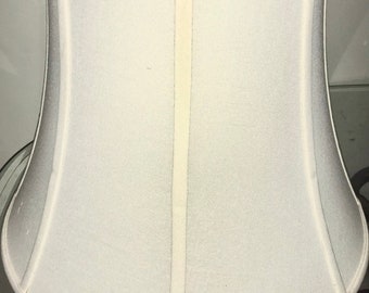 May include: A white lampshade with a bell shape and a seam down the center.