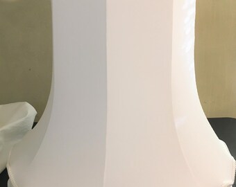 May include: A white lampshade with a scalloped edge and a decorative trim. The lampshade has a unique shape, wider at the bottom and narrower at the top. The fabric appears to be a soft, opaque material.