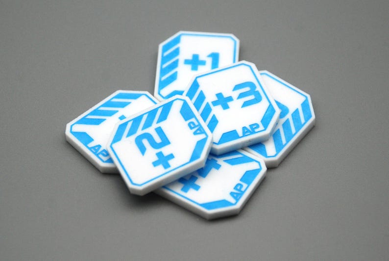 May include: A collection of white octagonal game tokens featuring blue printed graphics. Each token displays a numerical value with a plus sign, such as +1, +2, or +3, alongside the letters AP. The tokens have a blue border and striped accents.