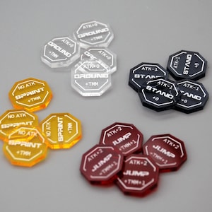 Pode incluir: Uma coleção de fichas de jogo acrílicas em várias cores, incluindo transparente, preto, vermelho e amarelo. Cada ficha tem texto branco indicando ações do jogo como "SPRINT", "STAND" e "JUMP".