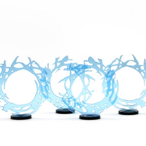 May include: Four blue translucent acrylic rings with a swirling, organic design. The rings are on black bases and are arranged in a row.