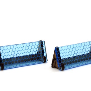 Può includere: Due espositori triangolari in acrilico blu con un motivo a nido d'ape. Gli espositori sono in legno e hanno un bordo nero.