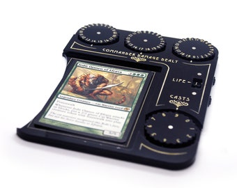 Op de afbeelding: Zwarte plastic game tracker met een kaartslot, wijzerplaten voor leven, worpen en toegebrachte schade, en de tekst "Commander Damage Dealt". Het kaartslot toont een Magic: The Gathering-kaart voor "Jedi  Ojaneen of Efrava".