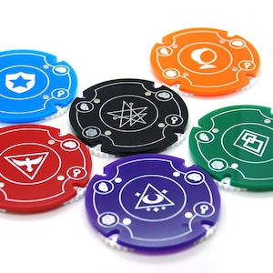 Può includere: Sei pezzi da gioco rotondi e colorati con diversi simboli al centro. Ogni pezzo ha un bordo bianco e un anello bianco di simboli attorno al bordo.