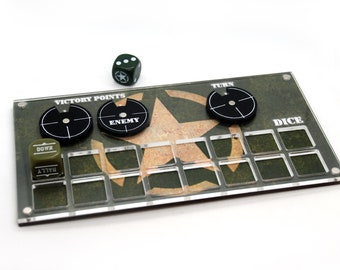 May include: A clear acrylic game board with a green and brown camouflage pattern. The board has a star in the centre and spaces for dice, victory points, and enemy tokens. The board also has the words "Victory Points", "Enemy", "Turn", "Dice", and "Down" printed on it.