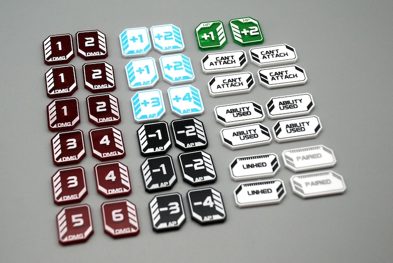 May include: A collection of game tokens featuring various colors and text. The set includes maroon DMG tokens, light blue AP tokens, green HP tokens, and white tokens labeled CAN'T ATTACH, ABILITY USED, LINKED, and PAIRED with black and white accents.