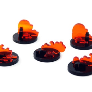 Puede incluir: Cinco fichas de fuego de acrílico naranja sobre bases negras. Las fichas de fuego tienen forma de llamas.