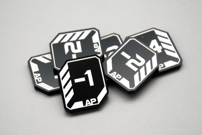 May include: A collection of black, octagonal game tokens featuring white printed graphics. Each token displays a numerical value, such as -1, -2, or 4, alongside the text AP and white diagonal striped accents on the corners of the game pieces.