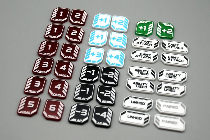 May include: A collection of game tokens featuring various designs. Dark red tokens are marked with numbers 1 through 6 and DMG. Light blue tokens show +1, +2, +3, +4 and AP. Black tokens show -1, -2, -3, -4 and AP. White tokens display CAN'T ATTACH, ABILITY USED, LINKED, or PAIRED.