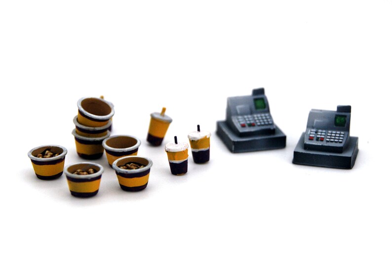 K&ouml;nnte beinhalten: Ein Miniatur-Set bestehend aus einer Kasse, einem Stapel kleiner gelber und schwarzer Becher und mehreren kleinen gelben und schwarzen Bechern, die mit braunen Gegenst&auml;nden gef&uuml;llt sind. Das Set ist aus Kunststoff und soll wie ein echtes Fast-Food-Restaurant aussehen.