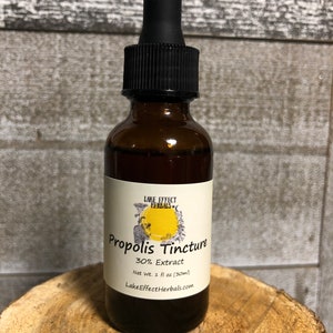 May include: A brown glass bottle with a black dropper top. The label reads "Lake Effect Herbals" and "Propolis Tincture 30% Extract Net Wt. 1 fl oz (30ml) LakeEffectHerbals.com".