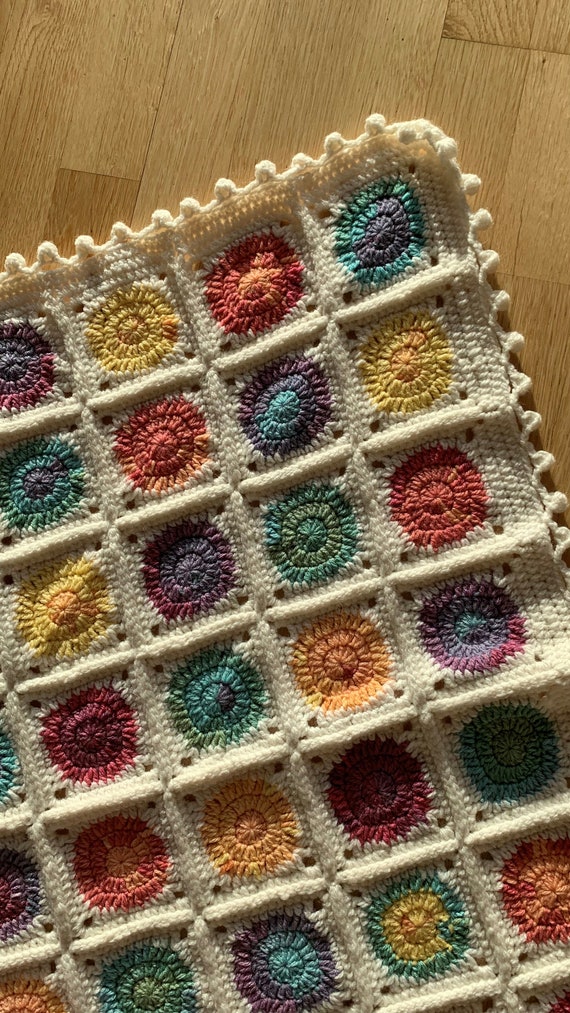 グラニースクエアベビーブランケットのカラフルな水玉模様とポンポン