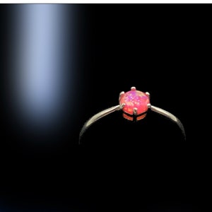 May include: A silver ring with a pink opal gemstone set in a prong setting.