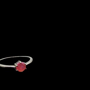 May include: A silver ring with a pink gemstone set in a prong setting.