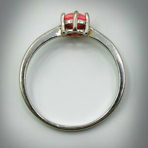 May include: A silver ring with a pink gemstone set in a prong setting.