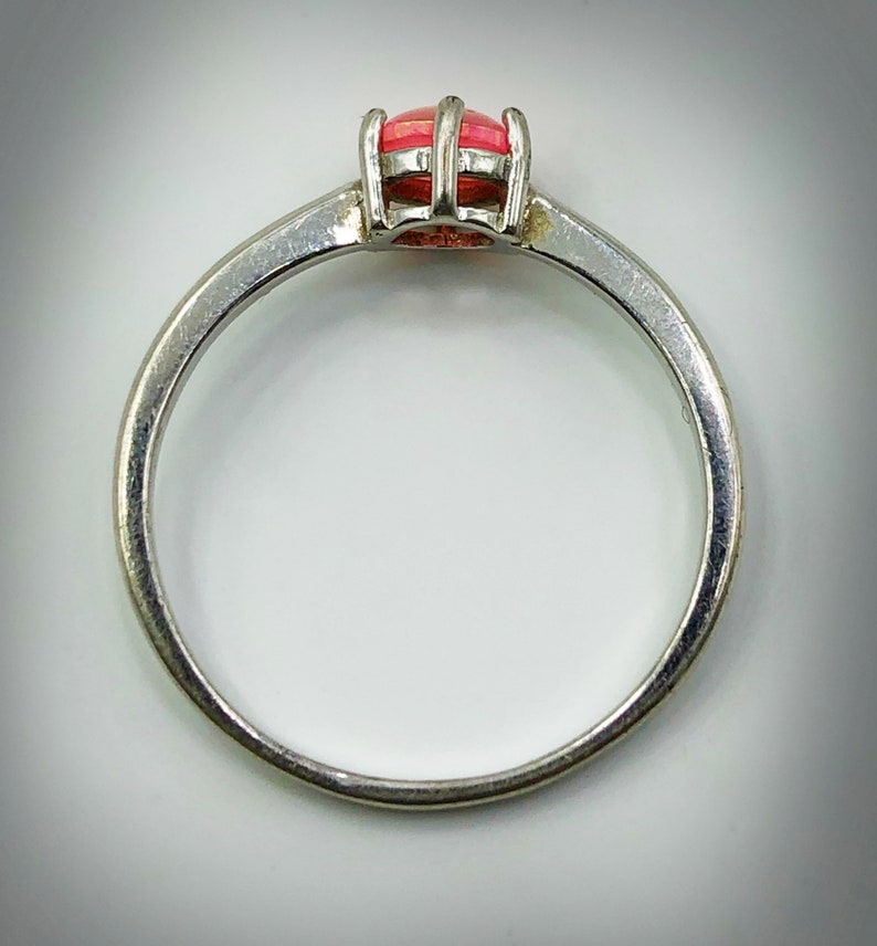 May include: A silver ring with a pink gemstone set in a prong setting.