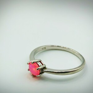 May include: A silver ring with a pink opal gemstone set in a prong setting.