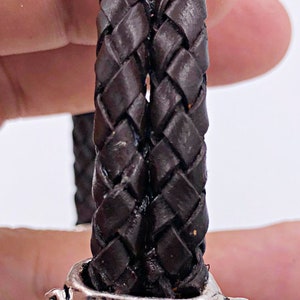 K&ouml;nnte beinhalten: Ein braunes Lederarmband mit einem silbernen, blattartigen Verschluss.