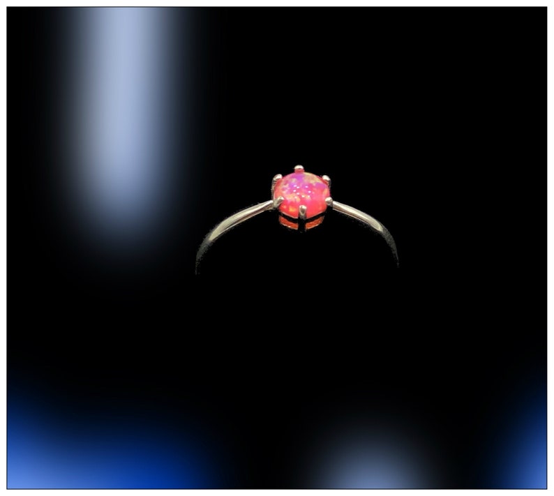 May include: A silver ring with a pink opal gemstone set in a prong setting.