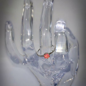 May include: A silver ring with a pink opal gemstone set in a prong setting.