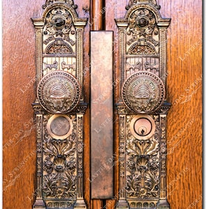 May include: Close-up of ornate brass door hardware on a wooden door. The hardware includes decorative plates with floral and geometric designs, along with a round door knob. The door hardware has the year 1853 and 1893 engraved on it.