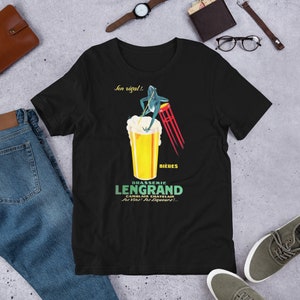 May include: Black t-shirt with a vintage-style illustration of a frog sitting on a bar stool and holding a beer glass. The text on the shirt reads "Brasserie Lengrand Camblain Chatelain.  Ser Vins! Ser Liqueurs! ..." and "Jen regal! ..."