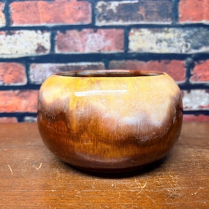 May include: A round ceramic bowl featuring a glossy glaze with a gradient transition from a deep, rich brown at the base to a lighter, creamy tan and white hue toward the top rim, showcasing a smooth, curved silhouette and a wide, open mouth.