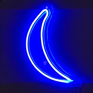 May include: A blue neon sign shaped like a banana. The sign is lit up and glowing against a dark background.