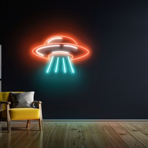 Puede incluir: Un letrero de ne&oacute;n con forma de platillo volante con luces naranja y azules sobre una pared oscura. El letrero est&aacute; colgado sobre un sill&oacute;n amarillo en una sala de estar.