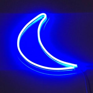 May include: A white neon crescent moon sign with a blue glow.