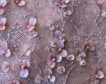 Puede incluir: Primer plano de una delicada tela rosa con un diseño floral. La tela está hecha de un material de malla transparente y está adornada con flores 3D y perlas.