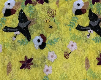 Puede incluir: Tela de encaje amarilla con pájaros negros, flores y hojas bordadas. La tela está adornada con cuentas y lentejuelas.