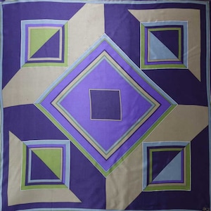 May include: A purple, blue, green, and brown geometric pattern on a square scarf. The pattern is made up of overlapping squares and diamonds.