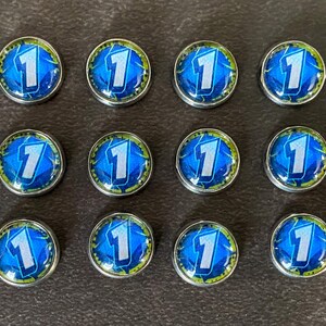 Puede incluir: Un conjunto de 17 fichas de juego azules y plateadas con los n&uacute;meros 1 y 3 impresos en ellas.