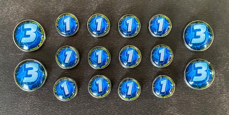 Puede incluir: Un conjunto de 17 fichas de juego azules y plateadas con los n&uacute;meros 1 y 3 impresos en ellas.