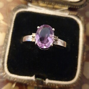 May include: A silver ring with a large oval amethyst gemstone and smaller accent stones.