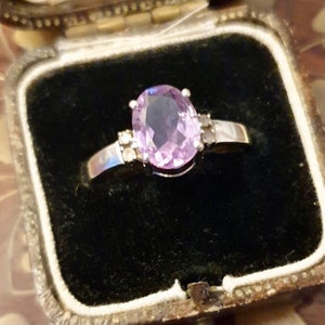 May include: A silver ring with a large oval amethyst gemstone and smaller diamond accents.