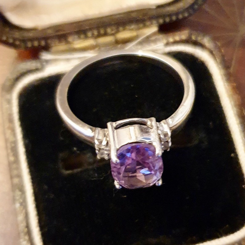 May include: A silver ring with a large oval amethyst gemstone and small diamond accents.
