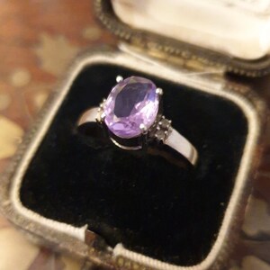 May include: A silver ring with a large oval-shaped amethyst gemstone and smaller diamond accents.