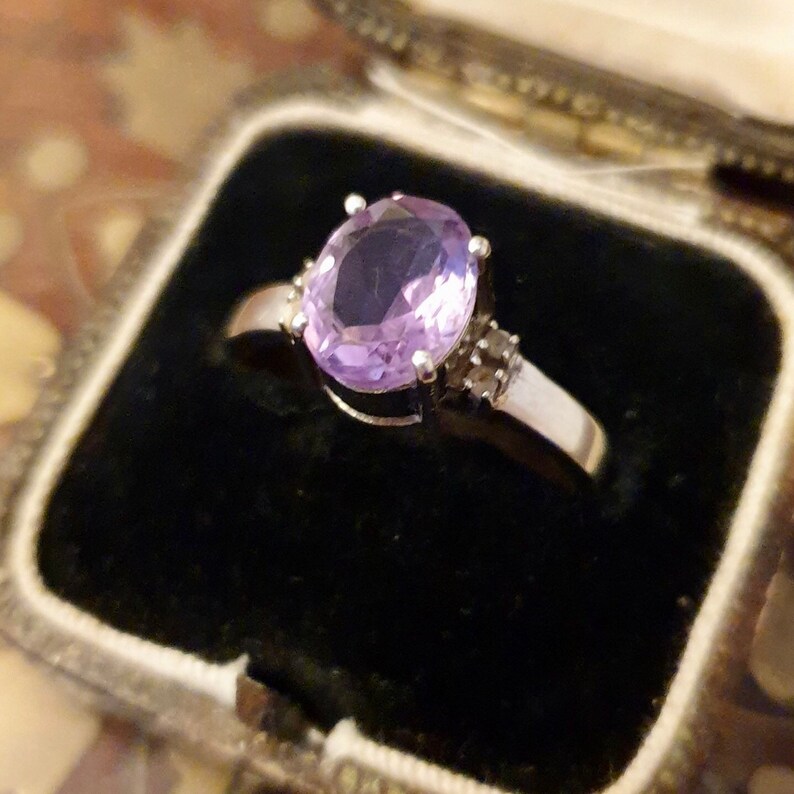 May include: A silver ring with a large oval amethyst gemstone and smaller diamond accents.
