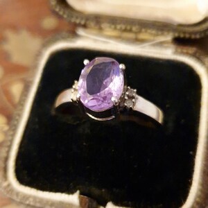 May include: A silver ring with a large oval amethyst gemstone and smaller diamond accents.
