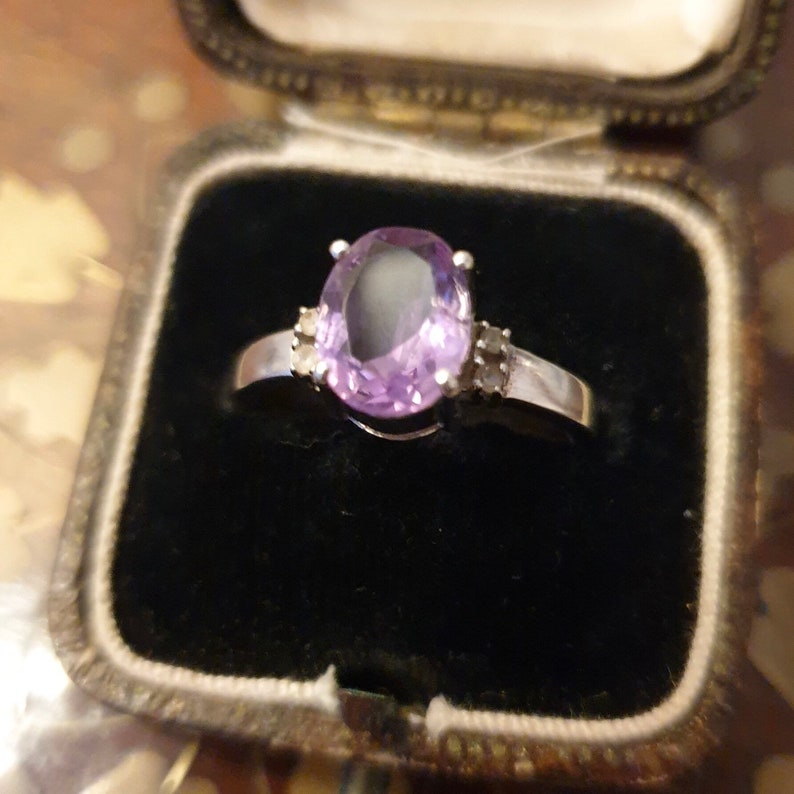May include: A silver ring with a large oval amethyst gemstone and smaller diamond accents.