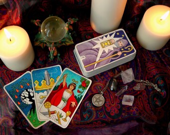 May include: A tarot card reading set up with four tarot cards, a crystal ball, two white candles, and crystals on a paisley patterned fabric. The cards show the Tower, the King of Swords, the Emperor, and the Star.